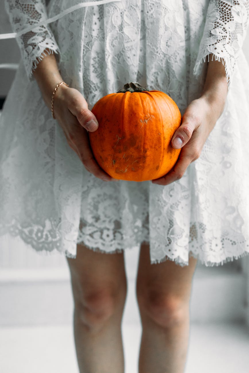 woman in white lace dress holding pumpkin